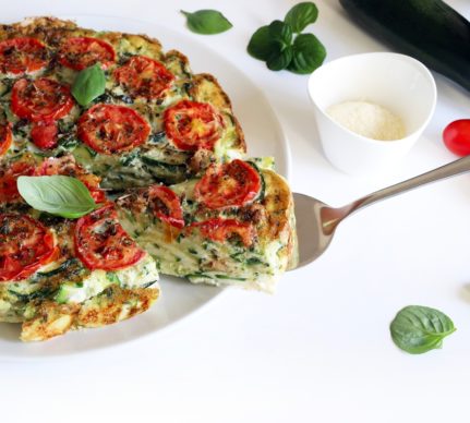 Frittata cu dovlecei și roșii, aromată cu busuioc, porționată pe o spatulă