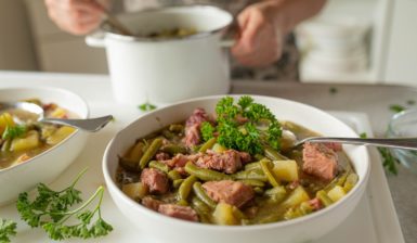Mâncare de fasole verde cu carne și cartofi în două boluri și în oală