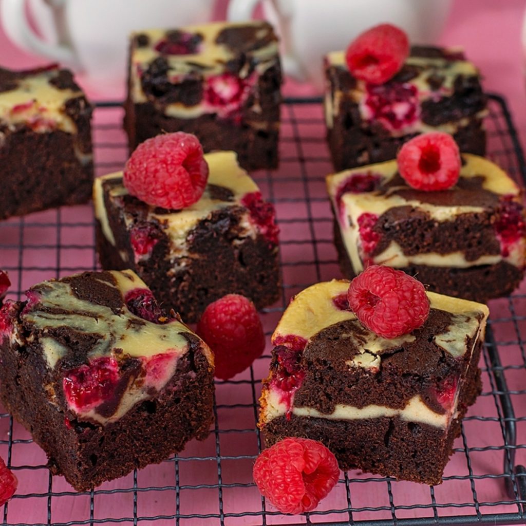 Porții de Cheesecake Brownie cu zmeură pe un grătar, decorate cu zmeură