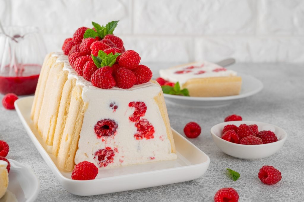 Prăjitură cu iaurt și zmeură porționată pe platou și pe farfurie