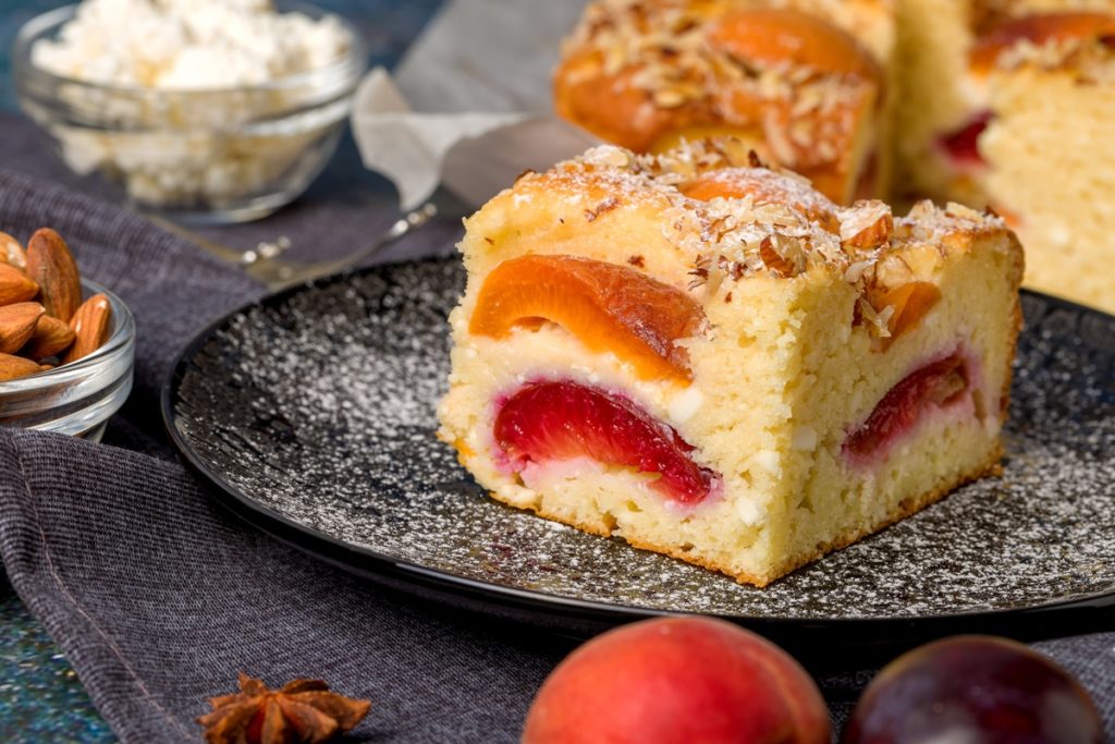 Porții de prăjitură umedă cu caise și nectarine, decorată cu migdale