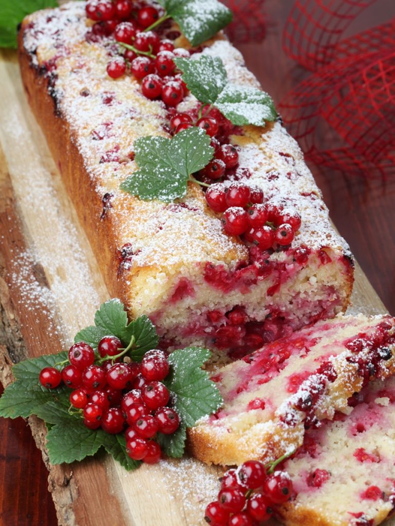 Chec cu cocos și coacăze roșii porționat pe un tocător