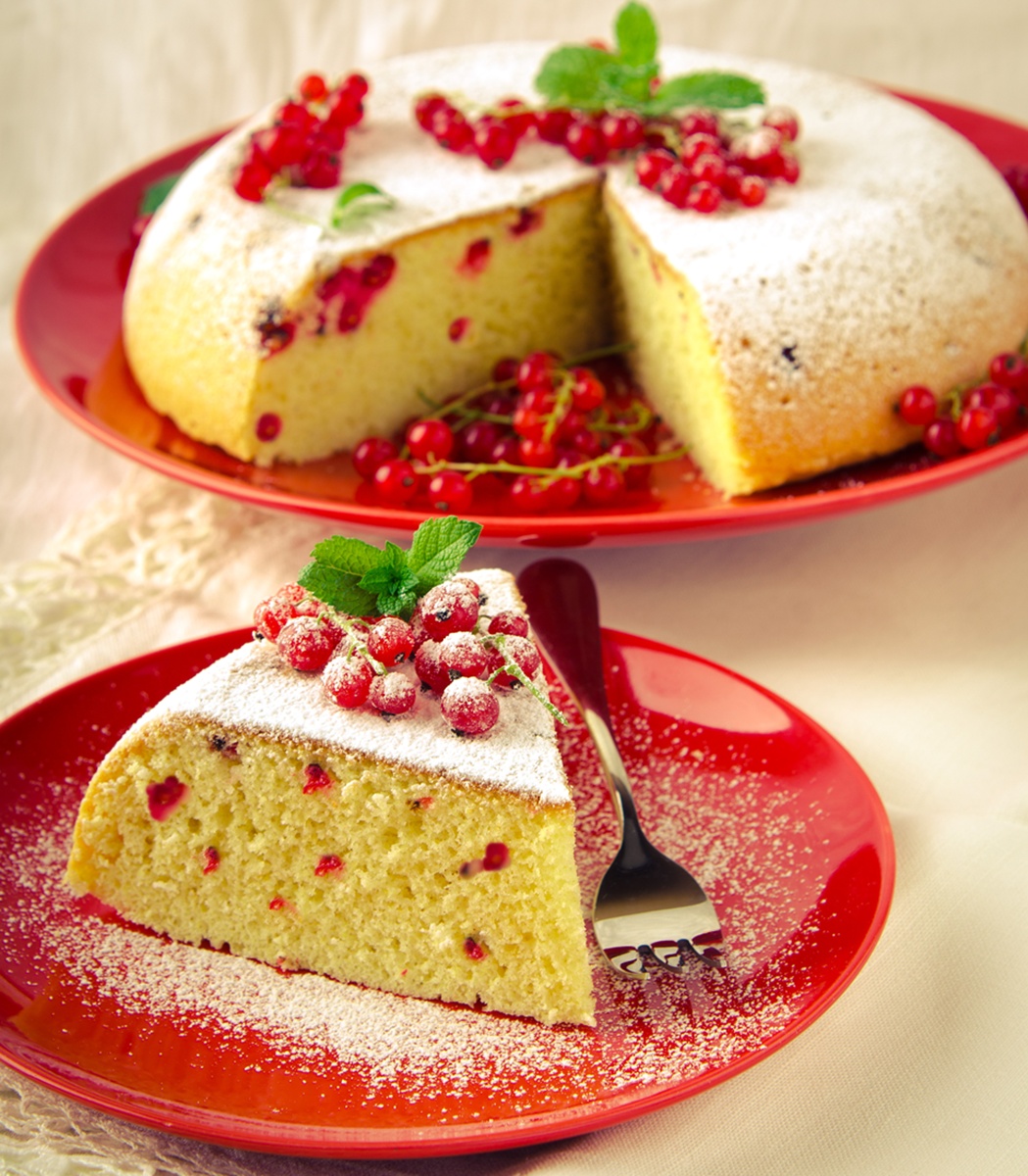 Pandișpan cu coacăze roșii porționat pe farfurie și pe platou