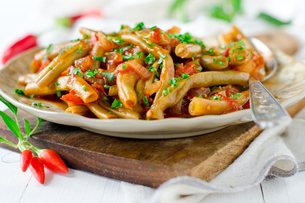 Fasole verde cu sos de ardei copți, decorată cu pătrunjel verde, tocat