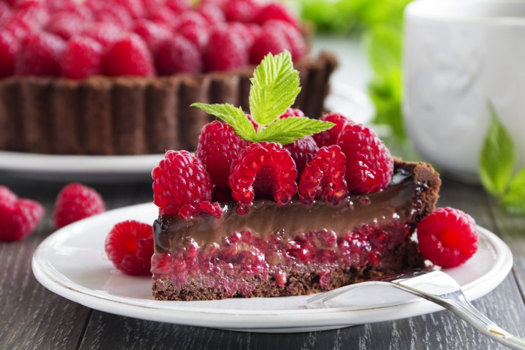 Tartă cu zmeură și cremă de ciocolată porționată pe o farfurie