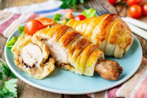 Două pulpe de pui în aluat, preparate la cuptor, una secționată
