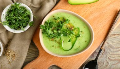 Gazpacho de avocado în bol, decorat cu ierburi, condimente și felii de avocado