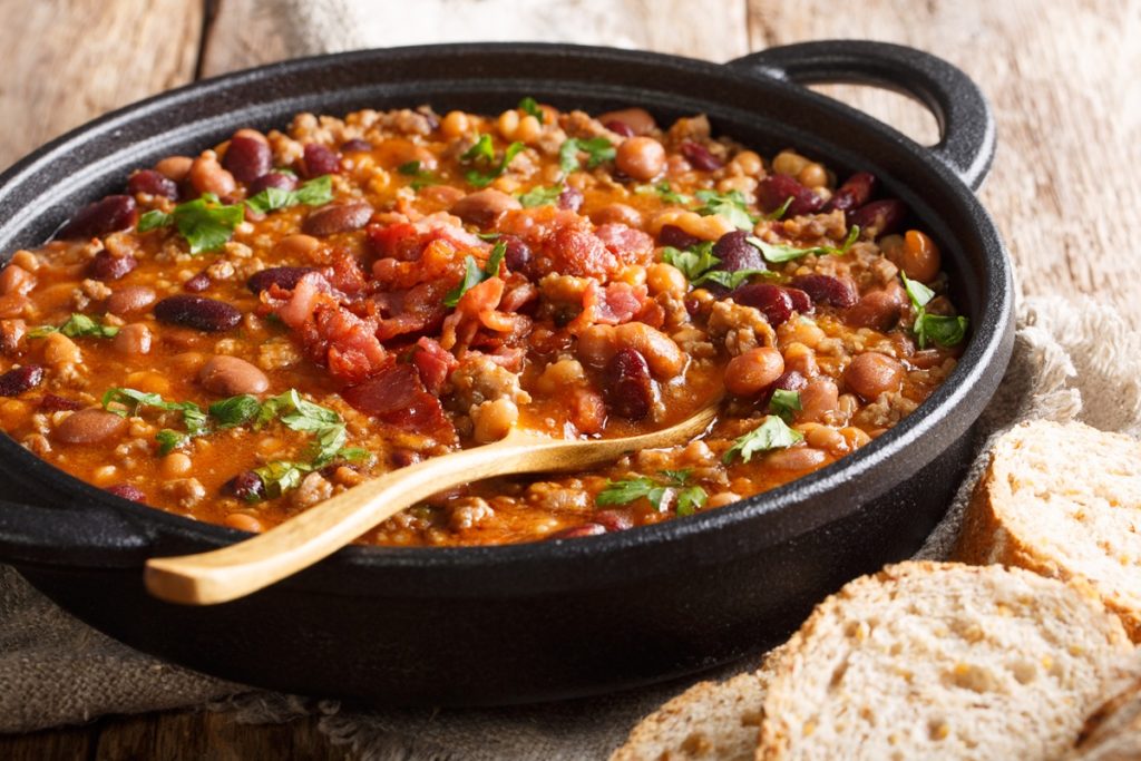 Iahnie de fasole cu bacon afumat în cratiță neagră cu lingură de lemn