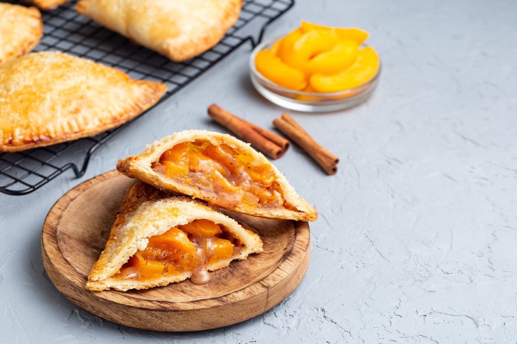 Pateuri triunghiulare cu caise secționate pe un platou de lemn