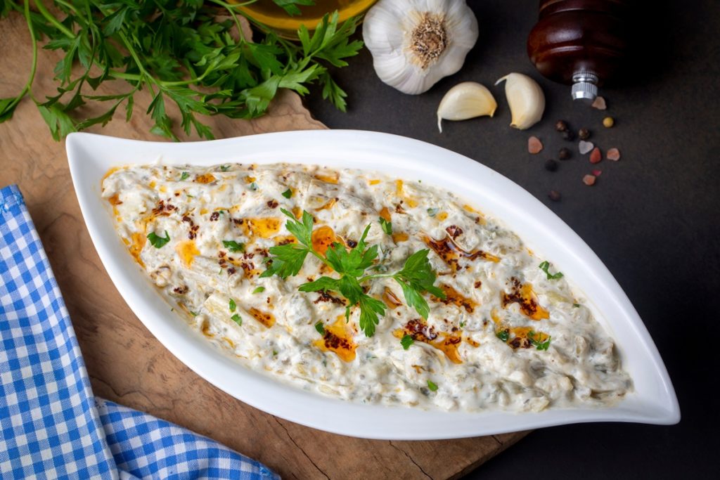 Salată de vinete cu iaurt și usturoi, decorată cu ulei și pătrunjel