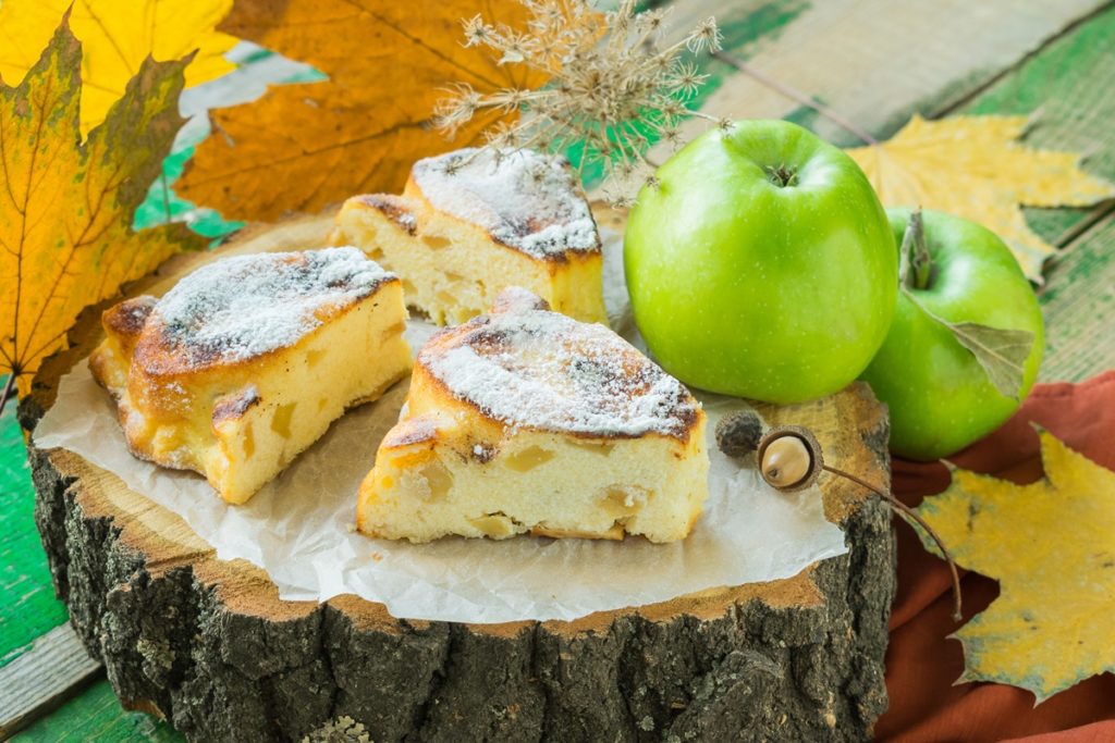 Porții de prăjitură cu brânză și mere cuburi și un măr verde