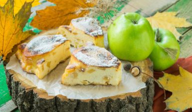 Porții de prăjitură cu brânză și mere cuburi și un măr verde