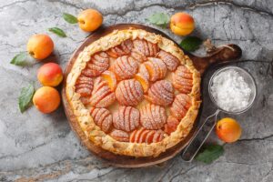 Tartă cu caise în formă de evantai pe un tocător de lemn