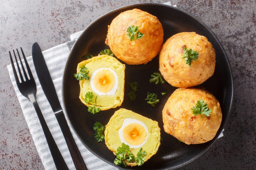 Patru ouă în crustă de cartofi piure, unul secționat