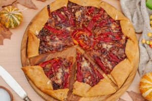 Galette cu dovleac în aluat și ardei copți cu brânză porționată pe un tocător de lemn