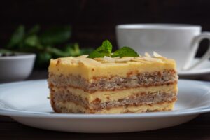 Prăjitură cu blaturi din albușuri cu nuci și cremă de gălbenușuri decorată cu migdale și frunze de mentă
