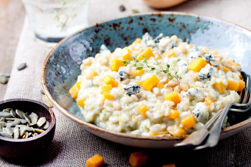 Risotto cu dovleac și gorgonzola în bol albastru și un bol cu semințe de dovleac