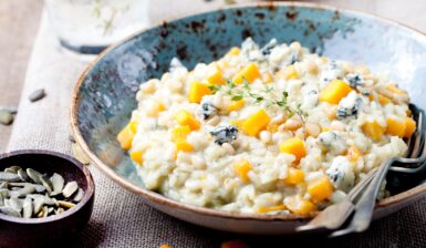 Risotto cu dovleac și gorgonzola în bol albastru și un bol cu semințe de dovleac