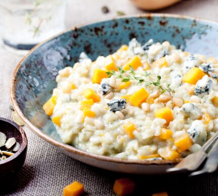 Risotto cu dovleac și gorgonzola în bol albastru și un bol cu semințe de dovleac