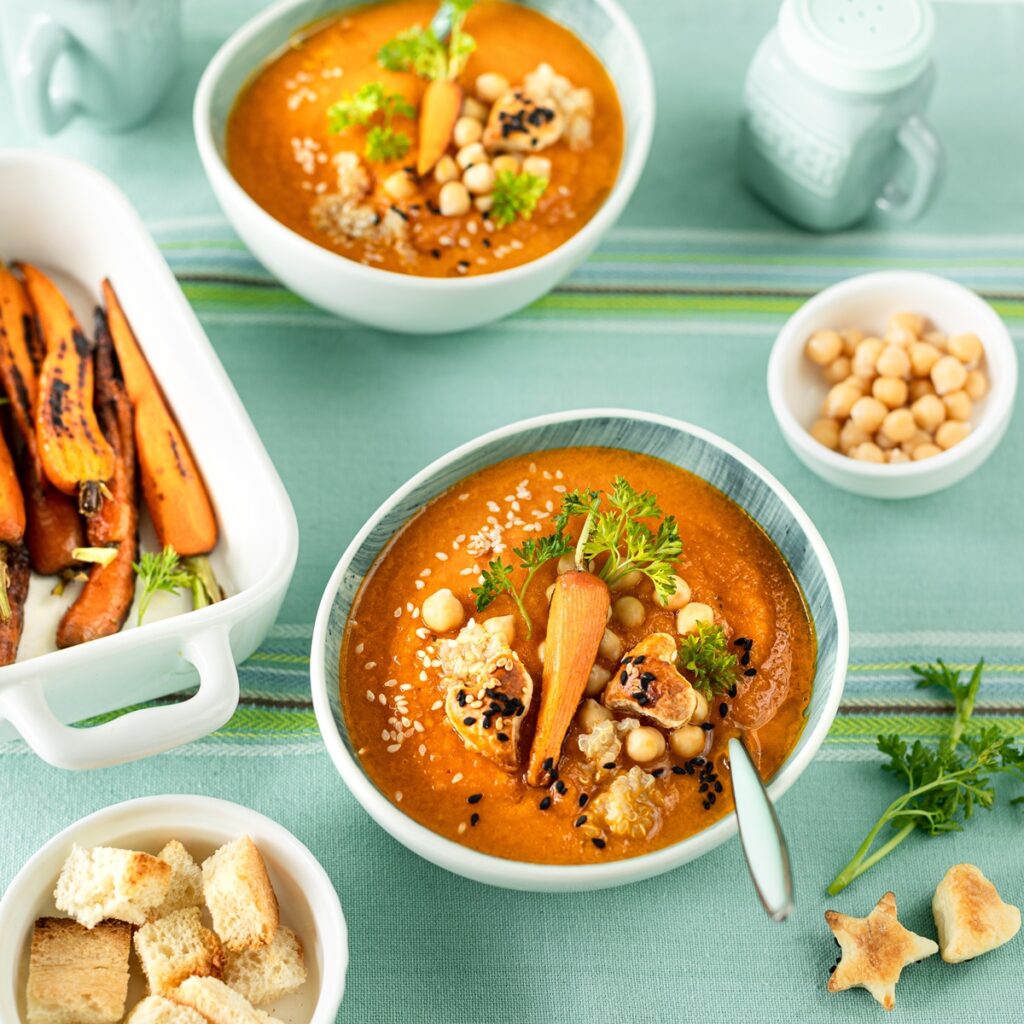 Supă cremă de dovleac cu morcovi și năut în două boluri, un bol cu năut, unul cu crutoane și altul cu morcovi caramelizați