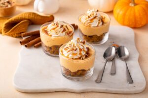 Trei pahare cu desert cu dovleac, cremă caramel și frișcă