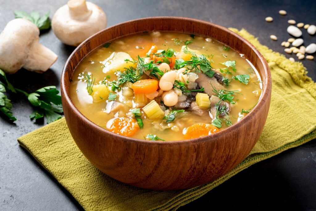 Supă rustică cu ciuperci și fasole albă în bol alb