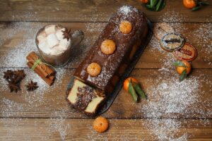 Chec cu brăduț de ciocolată în interior, glazurat cu ciocolată și decorat cu mandarine porționat pe platou