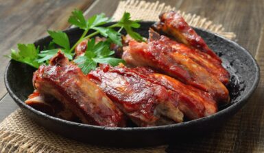 Coaste de porc prăjite în untură la tigaie, decorate cu pătrunjel verde