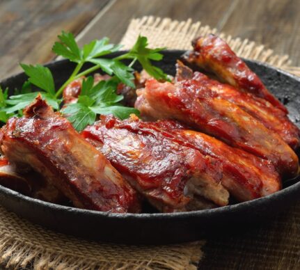 Coaste de porc prăjite în untură la tigaie, decorate cu pătrunjel verde