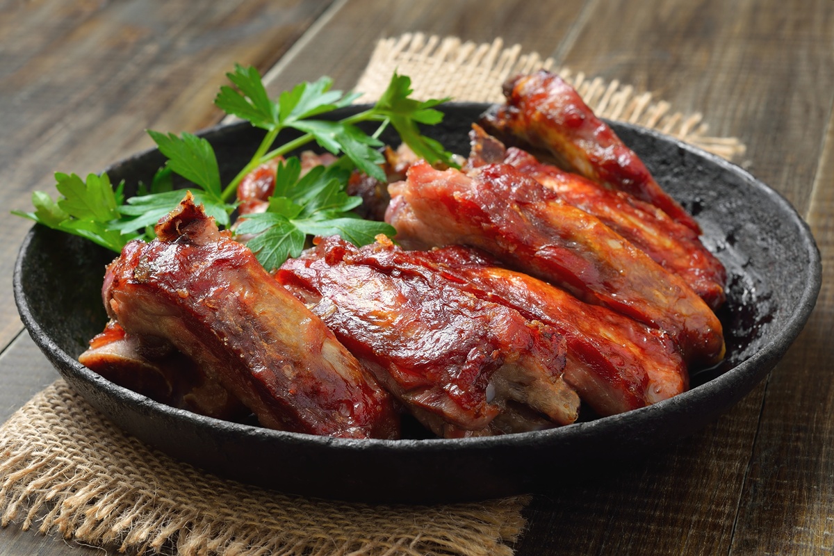 Coaste de porc prăjite în untură la tigaie, decorate cu pătrunjel verde