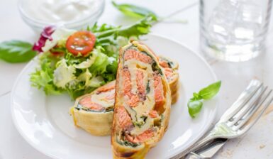 Două porții de ștrudel cu somon, spanac și cașcaval pe o farfurie cu salată