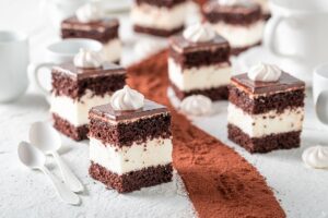 Prăjitură cu blat de cacao, cremă de vanilie și glazură subțire de ciocolată porționată