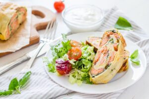Două porții de ștrudel aperitiv cu somon pe o farfurie cu salată