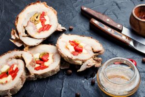 Patru felii de ruladă de porc cu gogoșari murați, măsline verzi și cașcaval