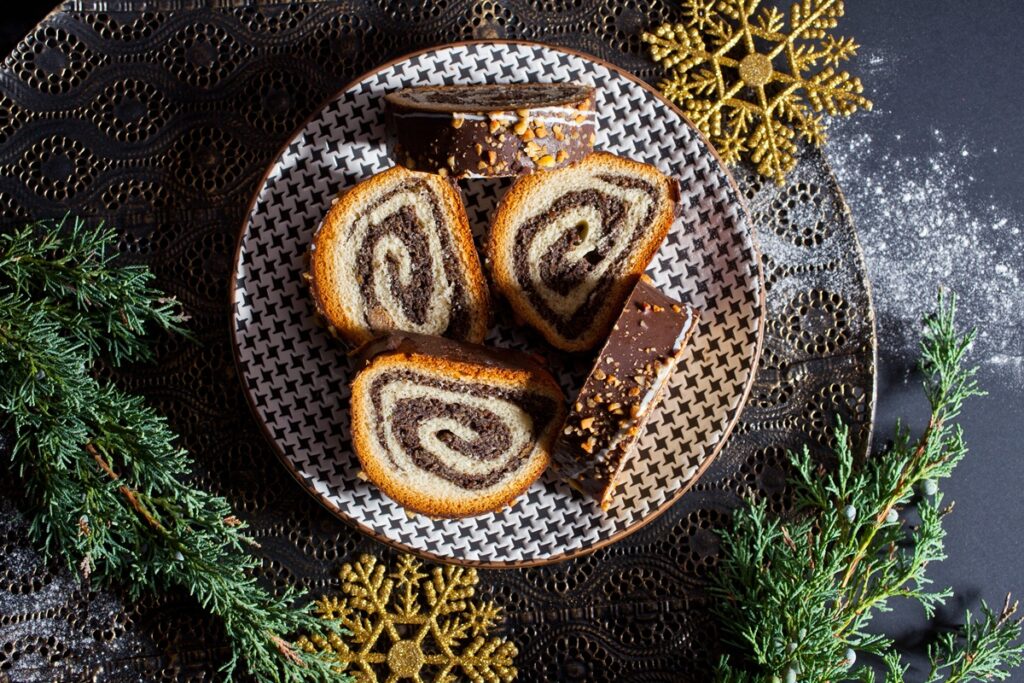 Porții de ruladă din aluat de cozonac cu nucă și cacao, glazurată cu ciocolată pe farfurie