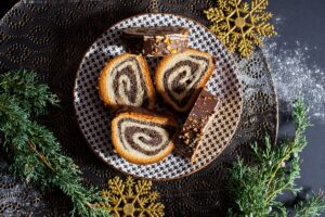 Porții de ruladă din aluat de cozonac cu nucă și cacao, glazurată cu ciocolată pe farfurie