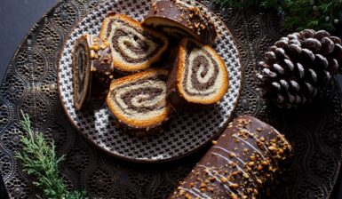 Ruladă din aluat de cozonac cu nucă și cacao, glazurată cu ciocolată porționată pe farfurie și o bucată neporționată