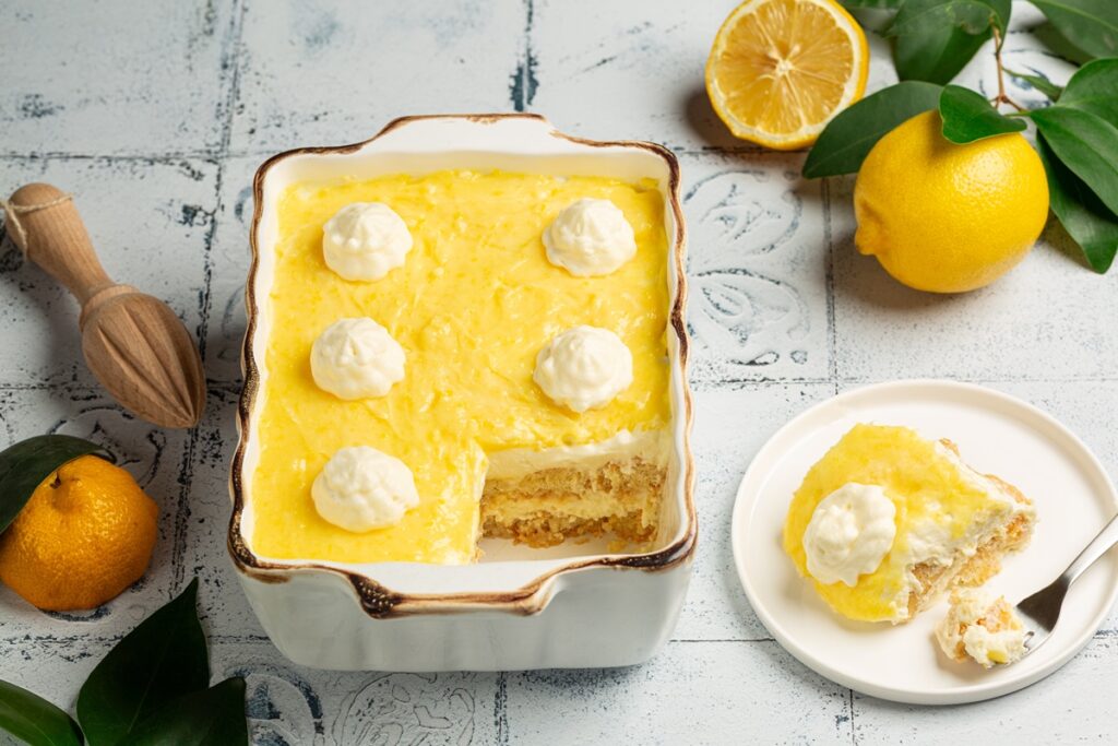 Tiramisu cu lămâie în tavă de porțelan și o porție pe farfurie