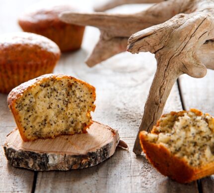 Brioșe cu lămâie și mac, una secționată pe un suport rustic de lemn