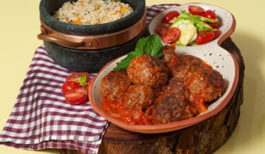 Chiftele în sos de ceapă caramelizată cu bulion, alături de un bol cu orez și unul cu salată