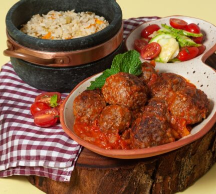 Chiftele în sos de ceapă caramelizată cu bulion, alături de un bol cu orez și unul cu salată