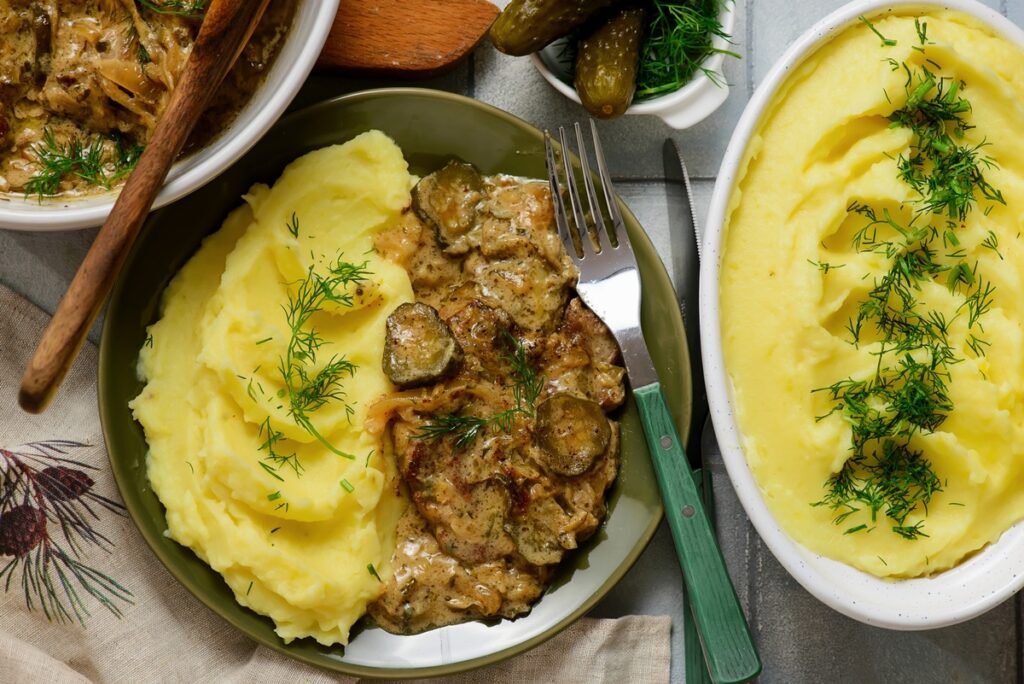 Friptură în sos cu varză călită, piure de cartofi și castraveți acri