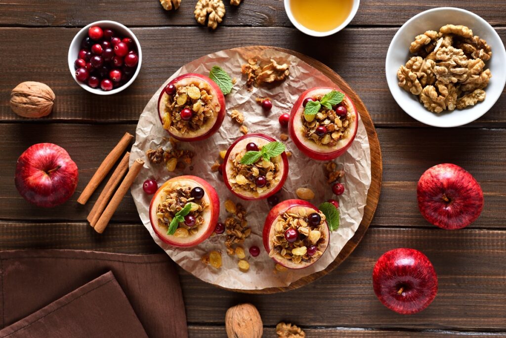 Cinci mere umplute cu granola, nuci și miere pe un platou