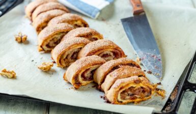 Ruladă fragedă cu gem și nuci porționată pe hârtie de copt