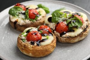 Trei ciuperci umplute cu brânză, roșii cherry și reducție de oțet balsamic