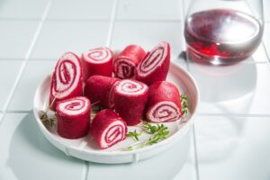 Clătite cu sfeclă și cremă de brânză porționate pe o farfurie și un pahar cu suc de sfeclă