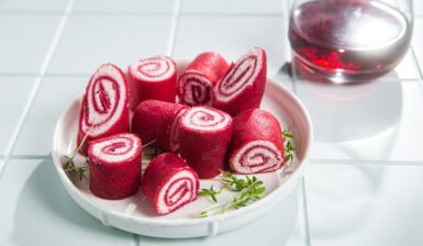 Clătite cu sfeclă și cremă de brânză porționate pe o farfurie și un pahar cu suc de sfeclă