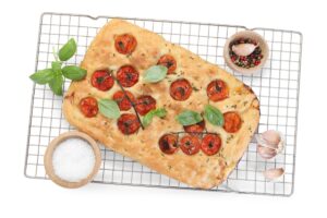 Focaccia cu roșii și frunze de busuioc pe un grătar