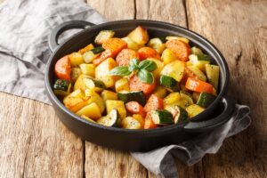 Cartofi cu morcovi și dovlecei în vas negru