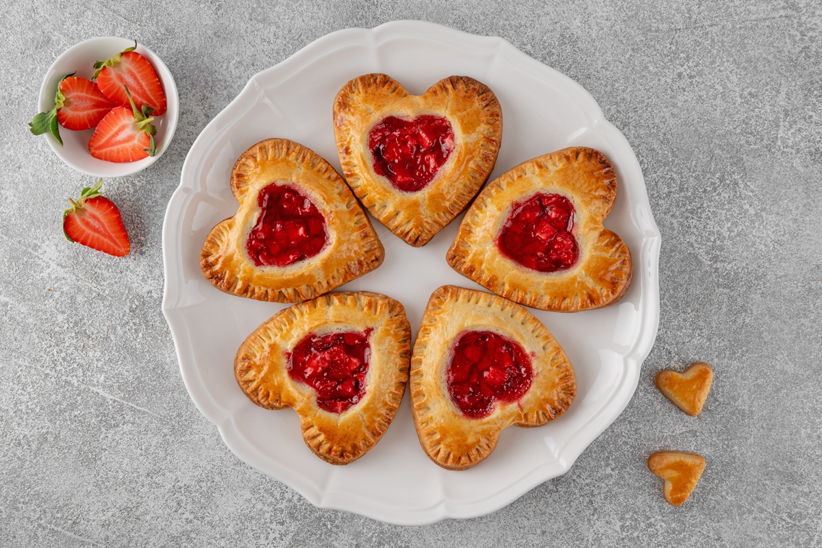 Cinci mini tarte inimioare din foietaj cu căpșuni pe o farfurie